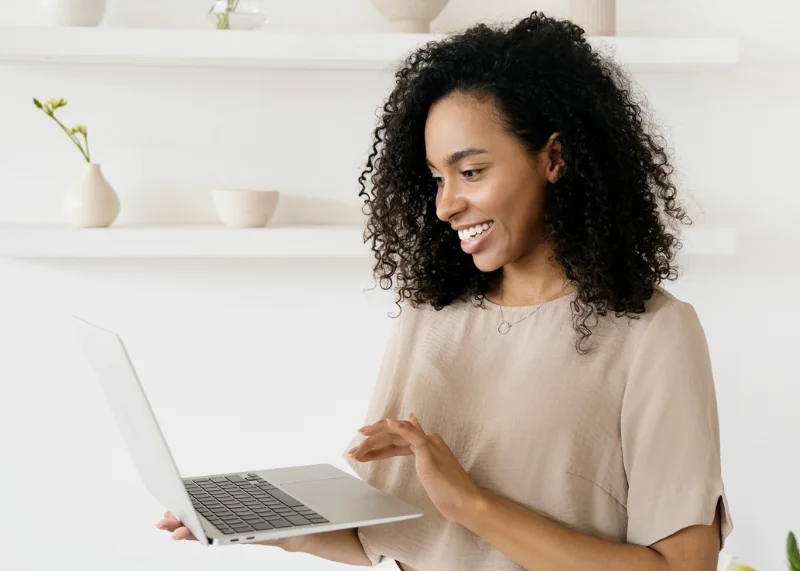 Mulher sorridente conferindo o feedback de sua loja online em seu notebook.