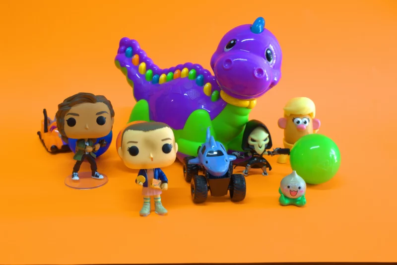 Personagens funko pop e outros brinquedos em fundo laranja.