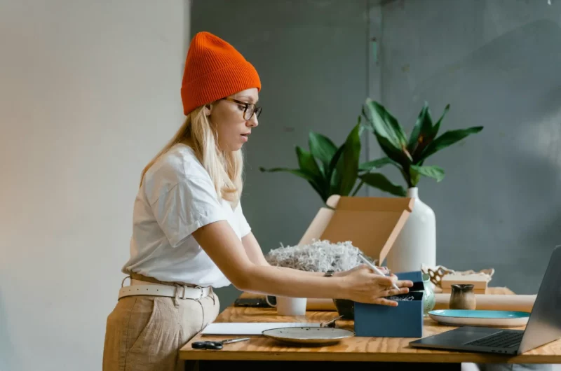 Jovem mulher organiza suas encomendas para envio.