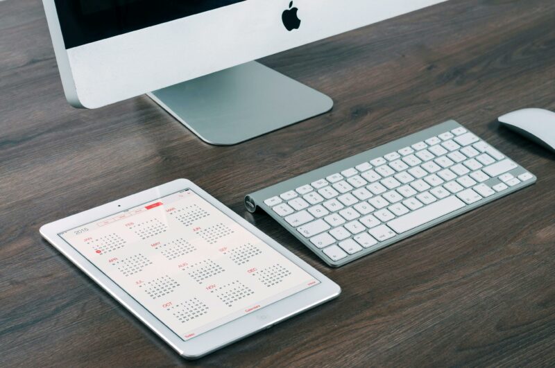 Mesa organizada com um calendário na tela de um iPad.