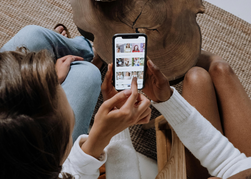 Como vender pelo TikTok: 7 dicas práticas para impulsionar seu e-commerce 1 Duas mulheres explorando o TikTok pelo celular, representando o uso da plataforma como canal de vendas, iilustrando o conteúdo sobre como vender pelo TikTok.