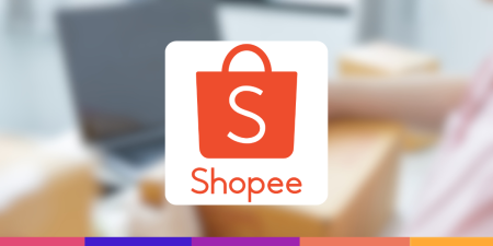 Logo da Shopee em destaque sobre fundo desfocado com ambiente de trabalho ao fundo, ilustrando o tema “taxa da Shopee” no contexto de vendas online.